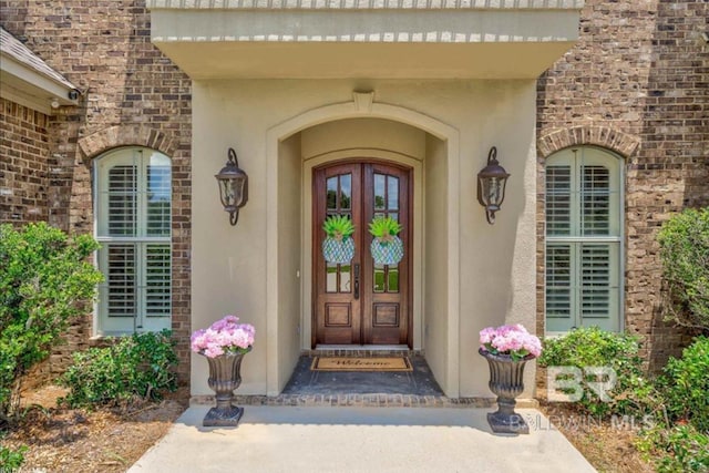 view of exterior entry featuring brick siding and stucco siding