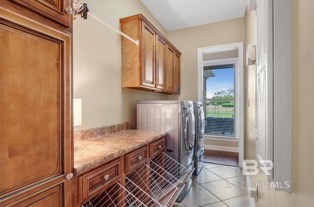 washroom featuring tile patterned floors, cabinet space, baseboards, and separate washer and dryer