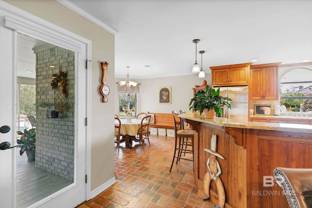 kitchen with crown molding, a healthy amount of sunlight, stainless steel fridge, and decorative light fixtures