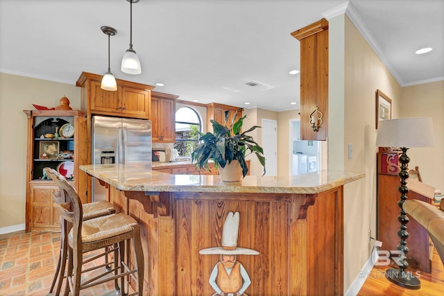 kitchen featuring stainless steel fridge, hanging light fixtures, light stone countertops, ornamental molding, and kitchen peninsula