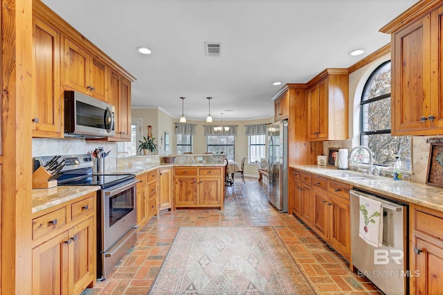 kitchen with pendant lighting, sink, appliances with stainless steel finishes, backsplash, and kitchen peninsula