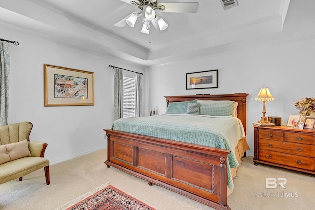 carpeted bedroom with ceiling fan and a tray ceiling