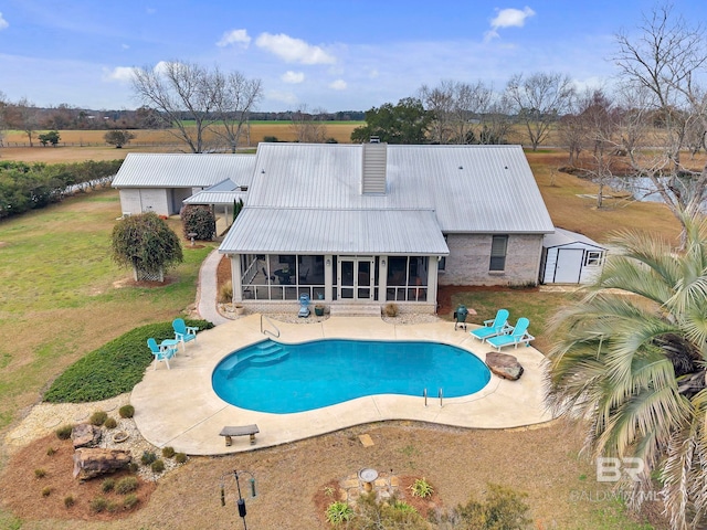 view of pool with a shed, a lawn, a sunroom, and a patio