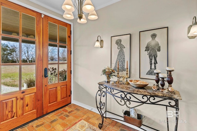 entryway with a healthy amount of sunlight, ornamental molding, and a chandelier