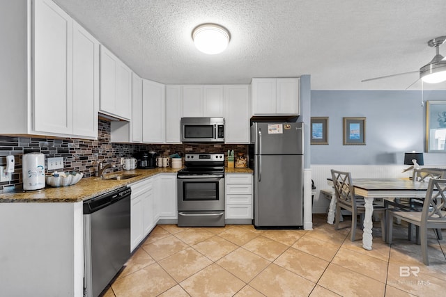 kitchen featuring white cabinets, sink, ceiling fan, dark stone countertops, and appliances with stainless steel finishes