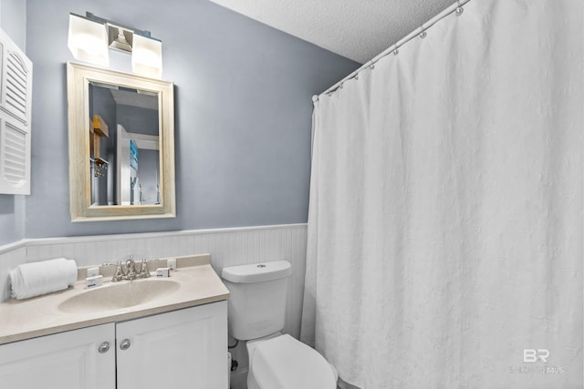 bathroom with vanity, toilet, and a textured ceiling