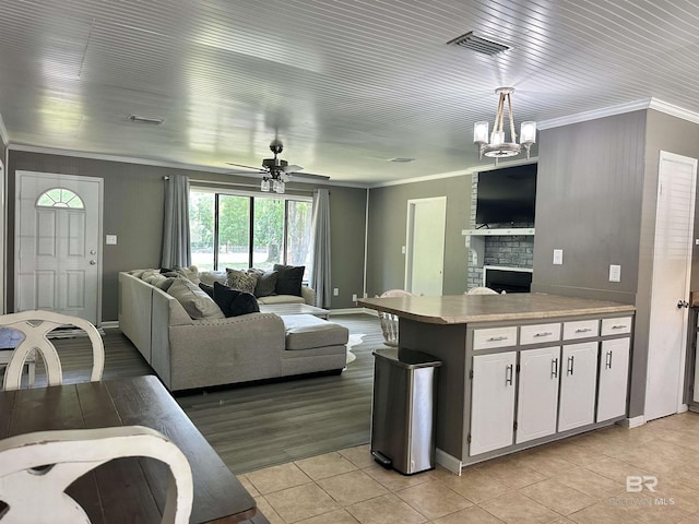 kitchen with light countertops, open floor plan, ornamental molding, and ceiling fan with notable chandelier