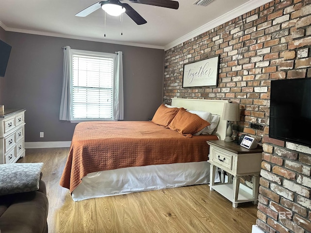 bedroom with brick wall, visible vents, wood finished floors, baseboards, and ornamental molding