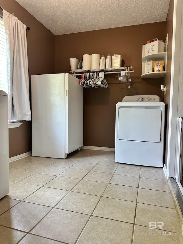 clothes washing area with laundry area, washer / dryer, baseboards, a textured ceiling, and light tile patterned floors