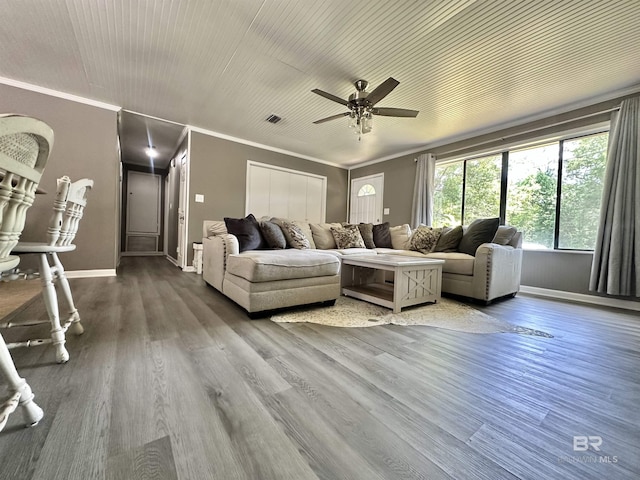 living area with a ceiling fan, baseboards, wood finished floors, visible vents, and ornamental molding