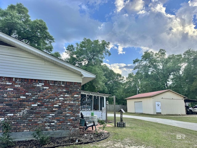view of property exterior featuring a detached garage, a lawn, an outbuilding, and a sunroom