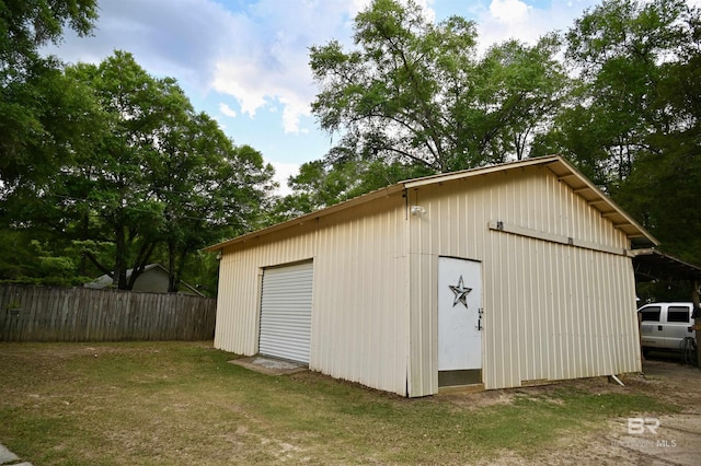view of outdoor structure featuring fence and an outbuilding