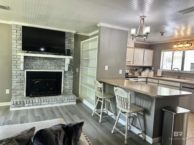 kitchen with crown molding, open floor plan, white cabinetry, a sink, and appliances with stainless steel finishes