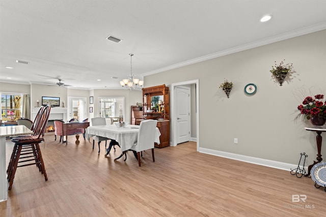 dining space with crown molding, light wood-style flooring, visible vents, and a wealth of natural light