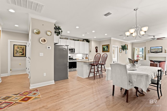 dining space featuring visible vents, light wood finished floors, and ornamental molding