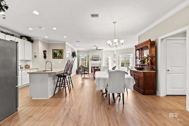 kitchen featuring visible vents, a kitchen bar, light wood-type flooring, ornamental molding, and freestanding refrigerator