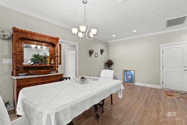 dining space featuring baseboards, visible vents, ornamental molding, light wood-type flooring, and a chandelier