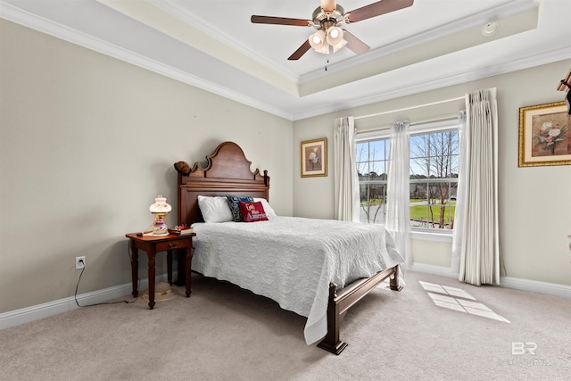 carpeted bedroom featuring a ceiling fan, a raised ceiling, baseboards, and ornamental molding