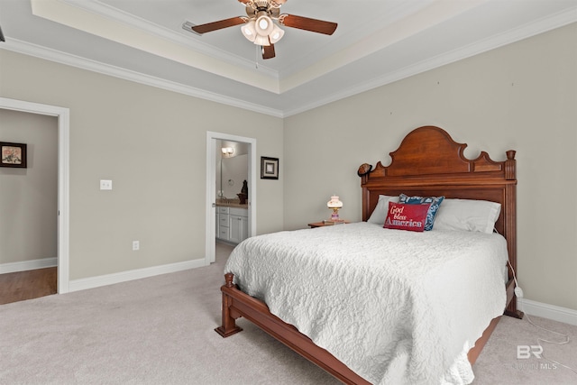 bedroom featuring ornamental molding, a tray ceiling, connected bathroom, carpet flooring, and baseboards