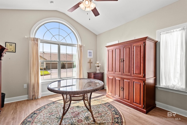 living area with baseboards, light wood finished floors, a ceiling fan, and vaulted ceiling