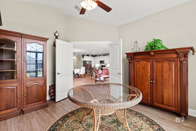 sitting room featuring visible vents, baseboards, vaulted ceiling, light wood-style floors, and a ceiling fan