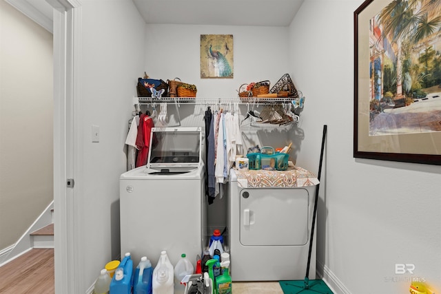 clothes washing area featuring laundry area, washer and dryer, baseboards, and wood finished floors