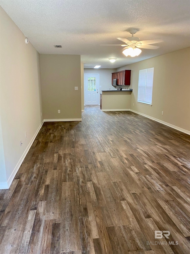 unfurnished living room with ceiling fan, dark hardwood / wood-style flooring, and a textured ceiling