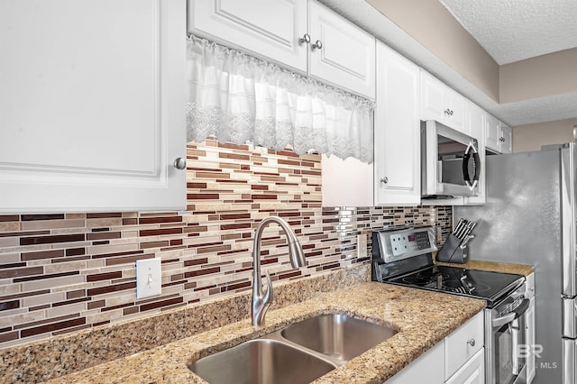 kitchen featuring stainless steel appliances, white cabinets, a sink, and backsplash