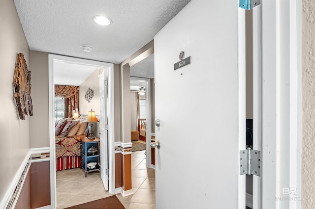 hallway with light tile patterned floors and a textured ceiling