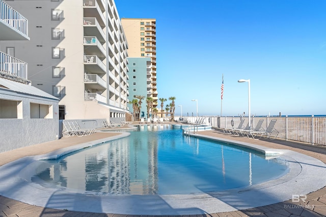 community pool with a patio area and fence