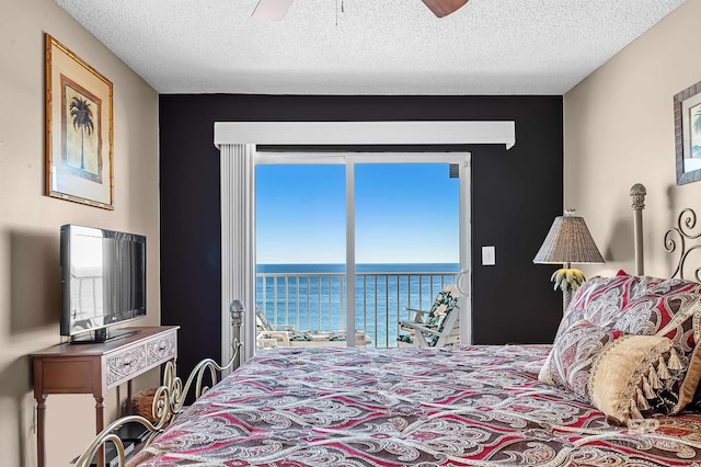 bedroom featuring a textured ceiling, ceiling fan, and a water view