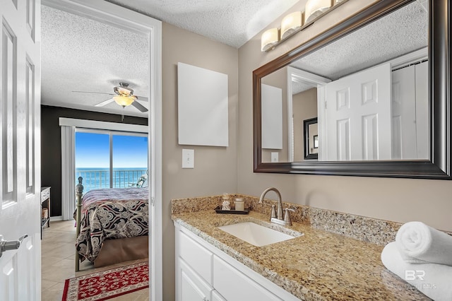 bathroom with ensuite bathroom, a textured ceiling, tile patterned flooring, a water view, and vanity