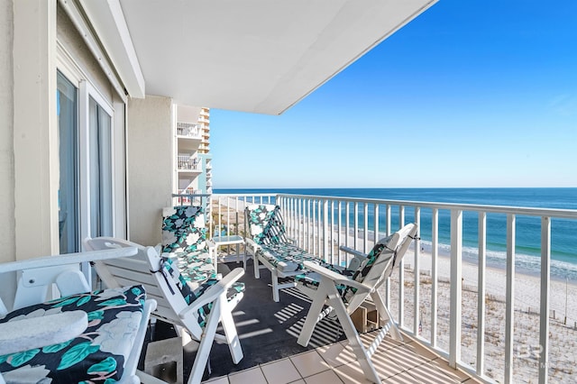 balcony featuring a view of the beach and a water view