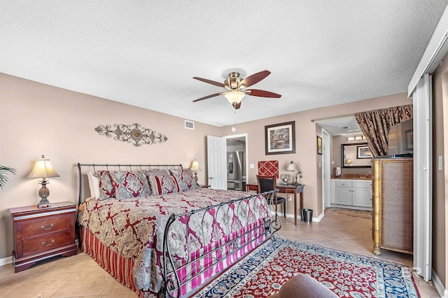 bedroom with a textured ceiling, light tile patterned flooring, visible vents, and baseboards