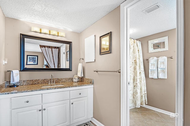 full bathroom featuring baseboards, visible vents, tile patterned floors, a textured ceiling, and vanity