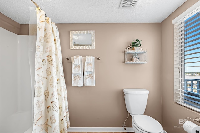 bathroom featuring curtained shower, visible vents, a textured ceiling, and toilet