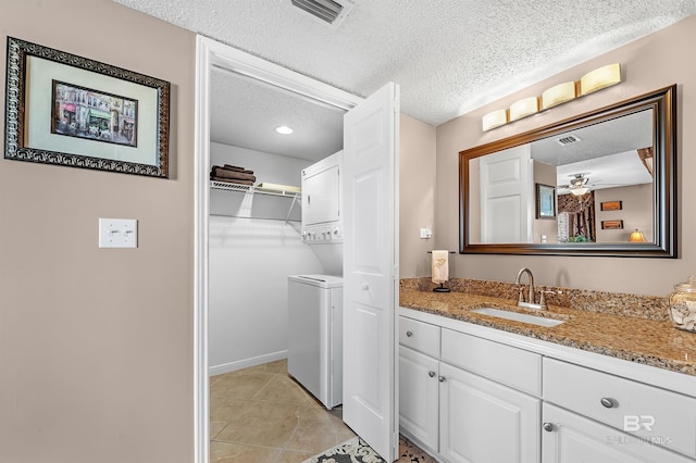 full bath featuring stacked washing maching and dryer, a spacious closet, visible vents, and a textured ceiling