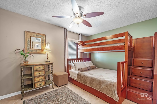 bedroom featuring a ceiling fan, baseboards, a textured ceiling, and light tile patterned flooring