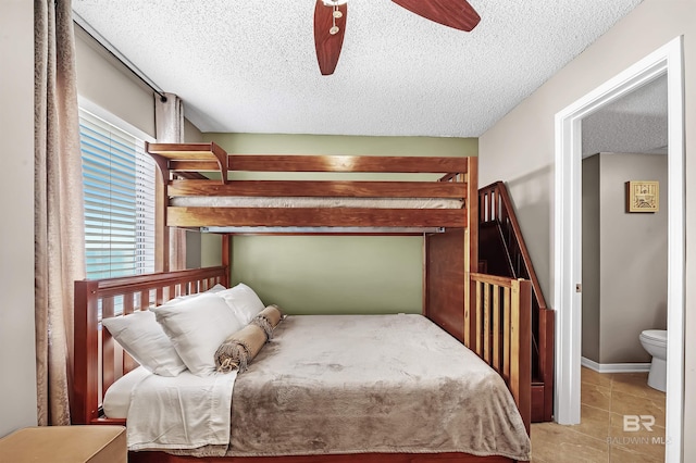 bedroom with light tile patterned floors, a textured ceiling, a ceiling fan, and baseboards