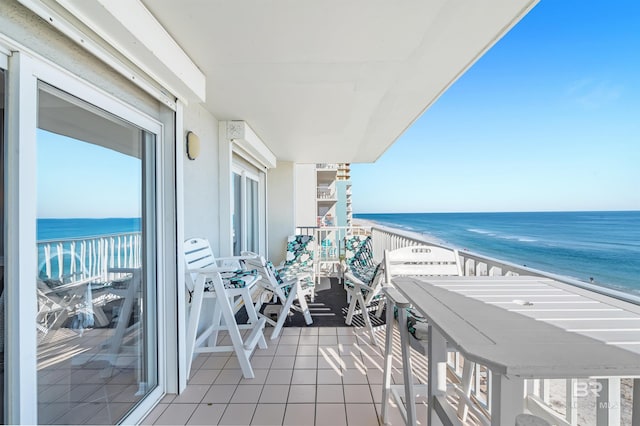 balcony with a water view and a view of the beach