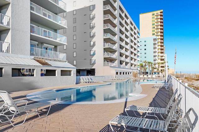 community pool with a patio area and fence