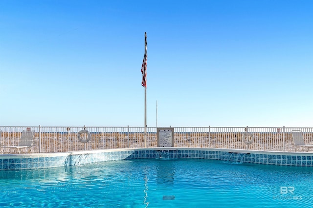 view of swimming pool with a water view and fence