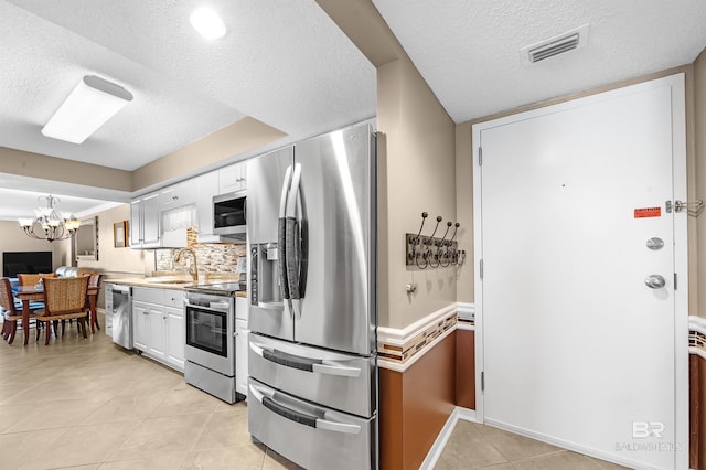 kitchen featuring visible vents, white cabinets, stainless steel appliances, light countertops, and a sink