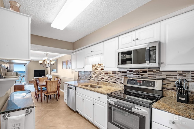 kitchen featuring dark stone counters, appliances with stainless steel finishes, a sink, and white cabinets