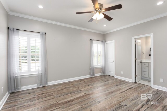 unfurnished bedroom featuring ceiling fan, hardwood / wood-style floors, ensuite bathroom, and multiple windows