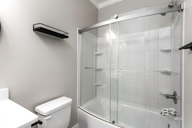 bathroom featuring enclosed tub / shower combo, crown molding, and toilet