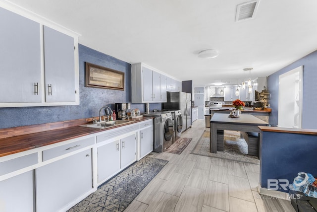 kitchen featuring an inviting chandelier, washing machine and clothes dryer, decorative light fixtures, and sink