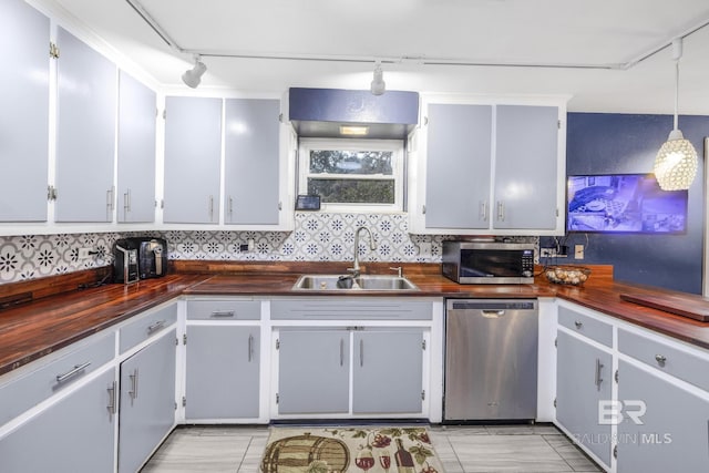 kitchen with butcher block countertops, sink, rail lighting, stainless steel appliances, and decorative light fixtures