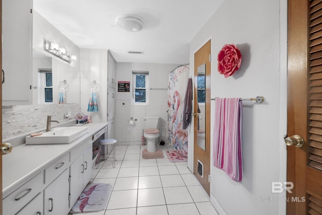 bathroom featuring tile patterned flooring, vanity, tasteful backsplash, toilet, and walk in shower