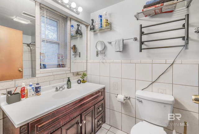 bathroom featuring vanity, tile walls, tile patterned floors, and toilet